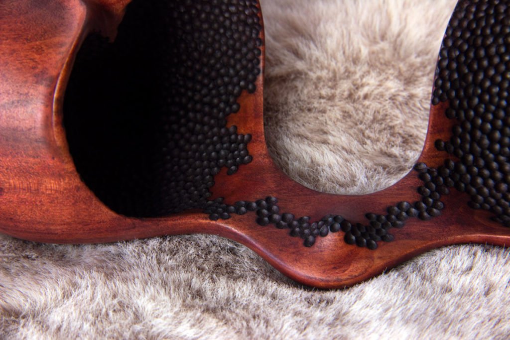 Vue détaillée de la sculpture tournée : "Graine d'Amoureux-ses" (Graine double creusée en forme de coeur, en pommier teintée et texture nid d'abeille pyrogravée à l'intérieur des parties creusées) - Création originale de Coralie Saramago