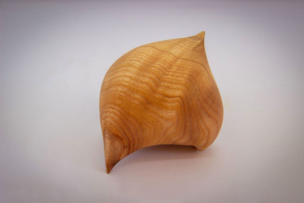 Vue du dos de la sculpture tournée : "Graine d'Amour" (sculpture sensorielle et ergonomique dans la main, inspirée par la forme du coeur, en frêne) - Création originale de Coralie Saramago